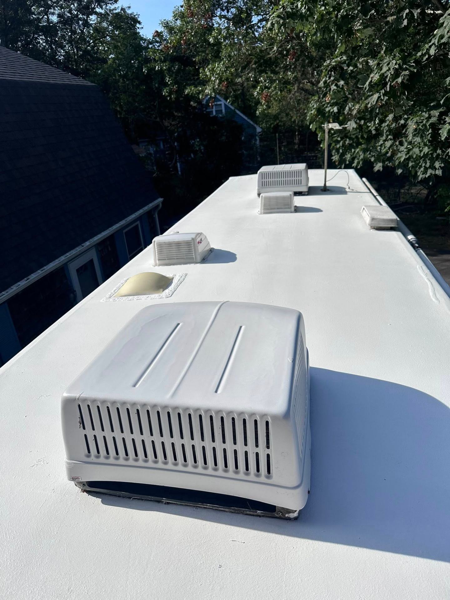 Full-length view of an RV roof showing A/C units, vents, and antenna after professional roof sealing service