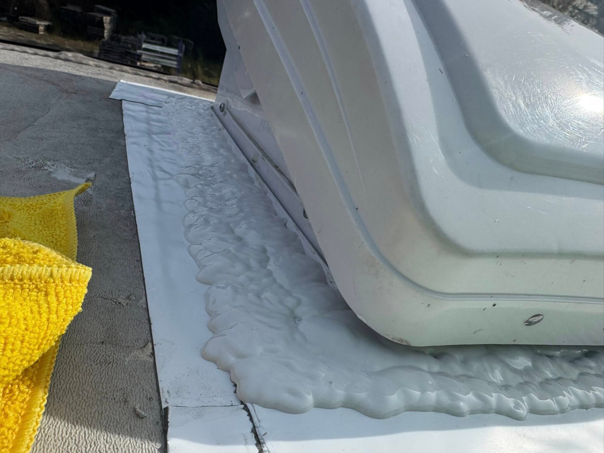 Close-up of fresh lap sealant applied around the base of an RV rooftop vent unit