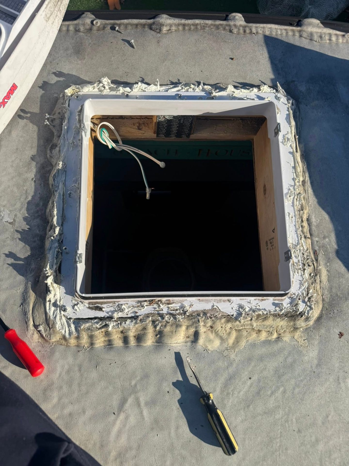 Old sealant being removed from an RV roof vent opening during a roof sealing job
